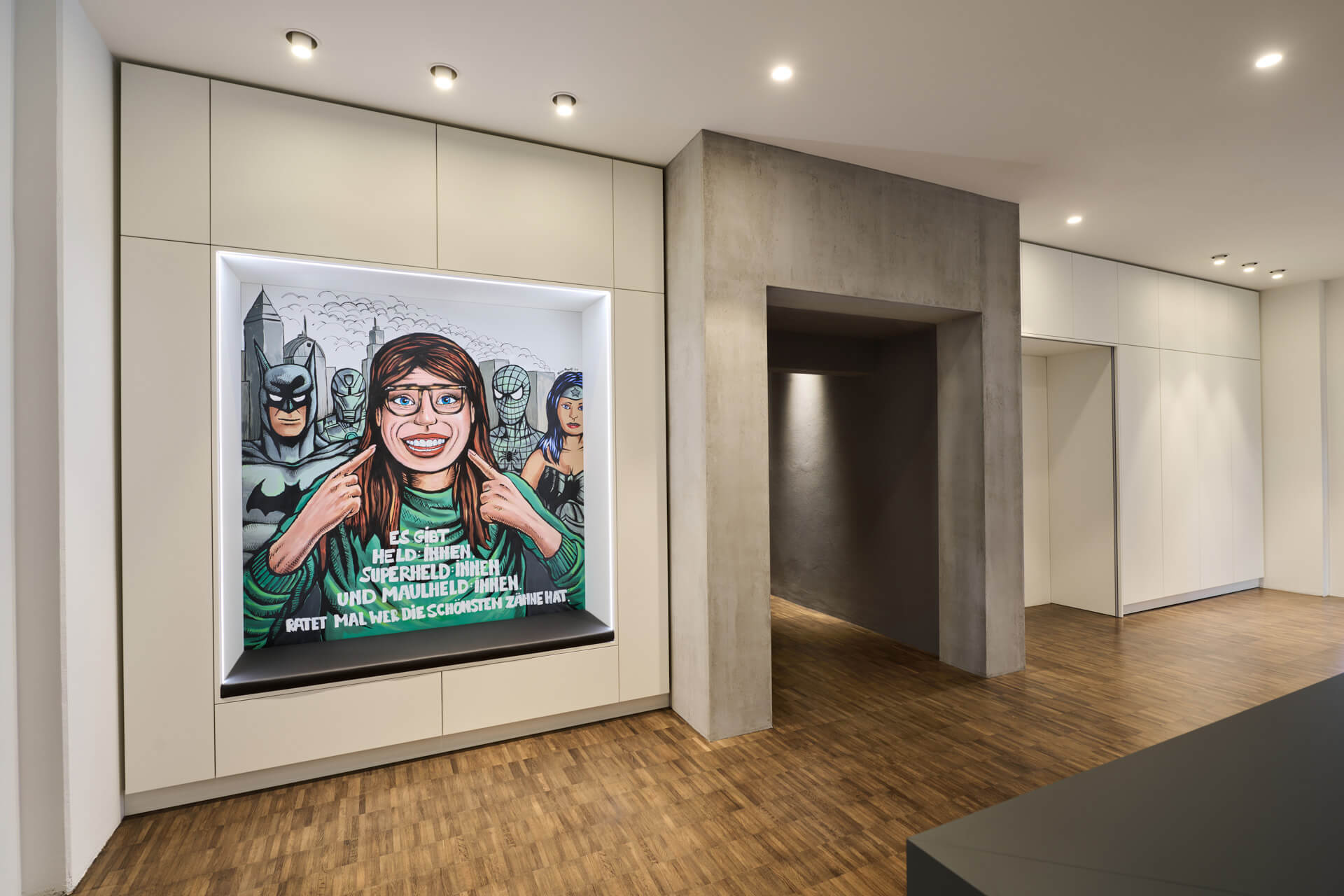 Empfangsbereich der Zahnarztpraxis maulheld:innen, an der Wand hängt ein Bild mit verschiedenen Superheld:innen und einer Maulheldin.