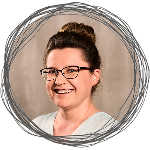 Elena Müller, zahnmedizinische Fachangestellte in der Zahnarztpraxis maulheld:innen in Nürnberg, fotografiert vor einer beigen Wand